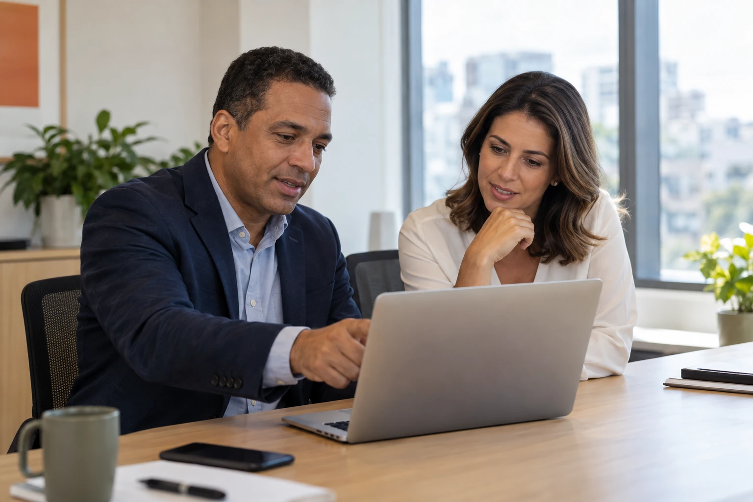 Gestor e consultora revisando uma proposta no notebook em um escritório claro